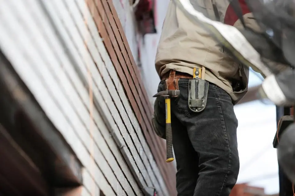 Tradesman in workwear with a tool belt and hammer working on a building site